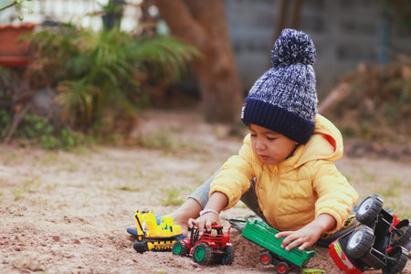 An Asian boy is playing with a toy car on the ground.