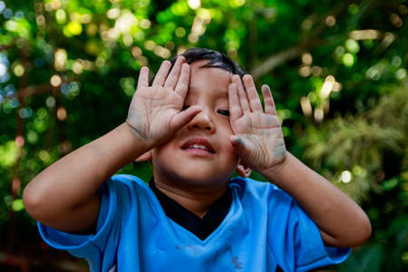 Asian boy plays  Hide and seek under the tree, close the eyes with handsの写真素材