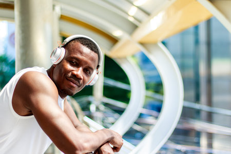 Portrait of a young African man wearing headphones and wearing a white tank top Looking at the...
