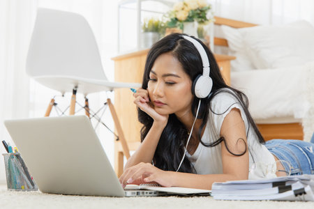 An Asian woman Education online from home. She student looking at laptop listening lecture study...