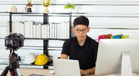 A young Asian man Works online from home. He earns money by teaching through live broadcasting through various Applications. He avoids the coronavirus outbreak. Concept Internet is everything.の写真素材