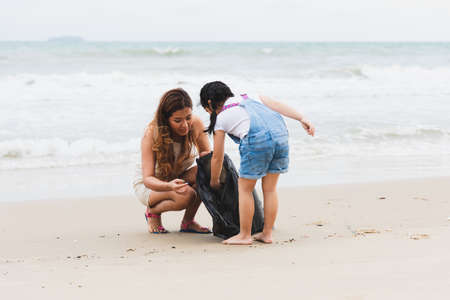 Asian family volunteers and children collecting garbage on the beach. Group of environmental help to keep nature clean up and pick up garbage. Concept of conservation and pollution problems.の写真素材