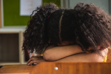 The girl african american elementary school kids asleep at classroom. She had a headache from...