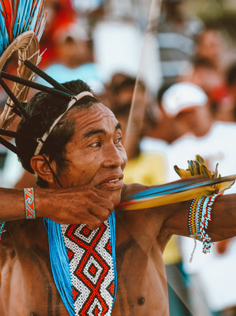 Indian man from an Amazon tribe in Brazil shooting with bow and arrow, wearing adornments and a cocar headdress. Jogos IndÃ­genas 2007.のeditorial素材