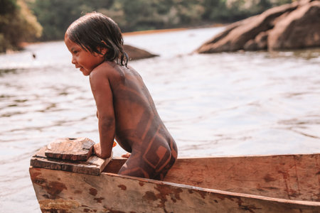 Indian child from the Asurini tribe in Brazil, playing inside a canoe in the Amazon River. 2010.のeditorial素材