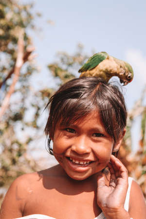 Brazilian Amazon Indian girl smiling and playing with bird. Xingu River, Amazon, Brazil. 2010.のeditorial素材