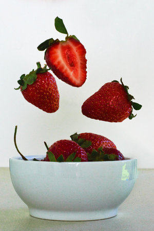 Strawberries falling into a bowlの写真素材