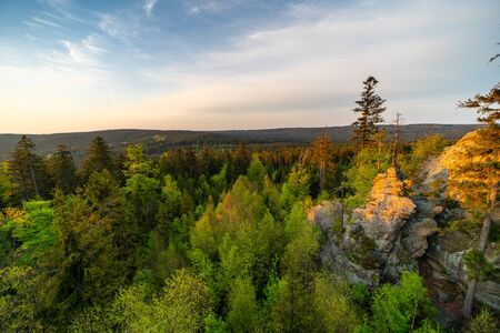 Sunbeams falling on rocks and forest at sunriseの写真素材