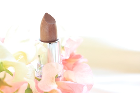 Lipsticks in beige color with flower on background for cosmetic imageの写真素材