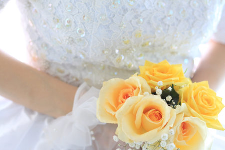 bride holding yellow roses wedding bouquet の写真素材