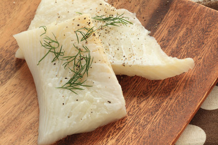 Herb and flat fish fillet prepared on wooden plate
