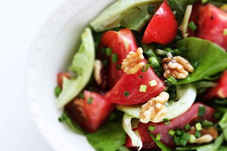 Tomato and walnut salad on white background with copy spaceの写真素材