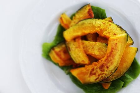 Pan fried pumpkin slices on white dishの写真素材