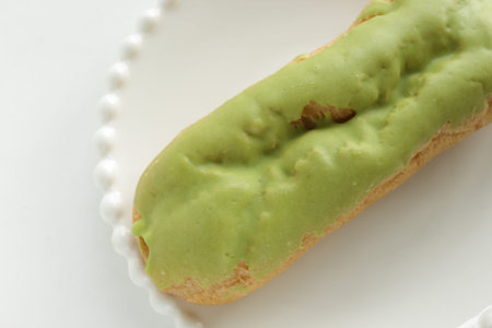 Green tea eclair puff cream confectionery on white dish with copy space