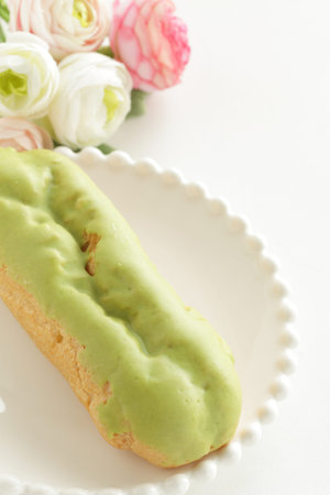 Green tea eclair puff cream confectionery on white dish with copy space