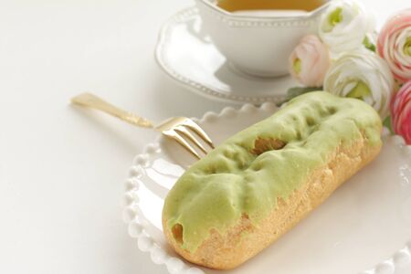 Green tea eclair puff cream confectionery on white dish with copy spaceの写真素材