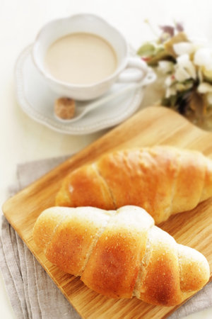 Butter and salt bun on wooden board and milk tea