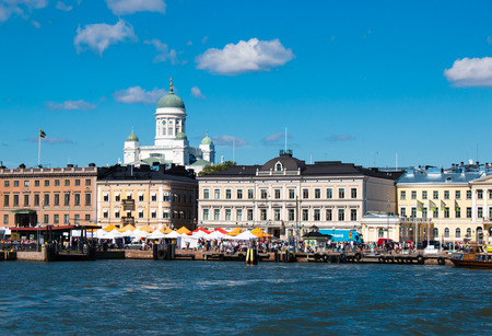 Iconic and beautiful Helsinki skyline featuring dome of Lutheran Cathedral, people sitting in cafeterias of Market Square, sunny weather with several clouds and blue skyのeditorial素材