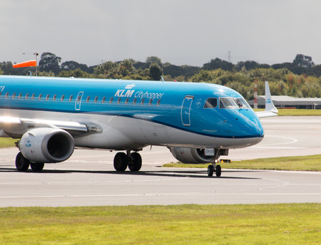 KLM Cityhopper Embraer ERJ-190 PH-EZB passenger plane taxiing on Manchester International Airport runway.のeditorial素材