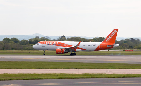 easyJet A320-214 narrow-body passenger plane (G-EZPC, in Europcar Livery) landing to Manchester International Airport runway.のeditorial素材
