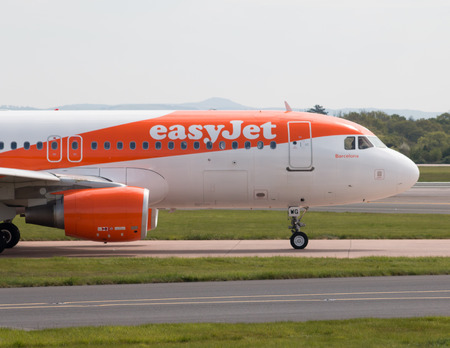 easyJet A320-214 narrow-body passenger taxiing on Manchester International Airport tarmac.のeditorial素材