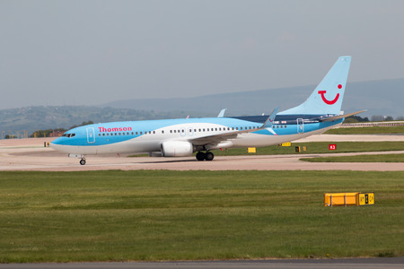 Thomson Airways Boeing 737-8K5 narrow-body passenger plane (G-TAWI) taxiing on Manchester International Airport tarmac.のeditorial素材