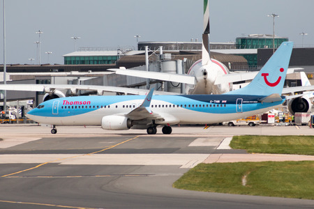 Thomson Airways Boeing 737-8K5 narrow-body passenger plane (G-TAWI) taxiing on Manchester International Airport tarmac.のeditorial素材