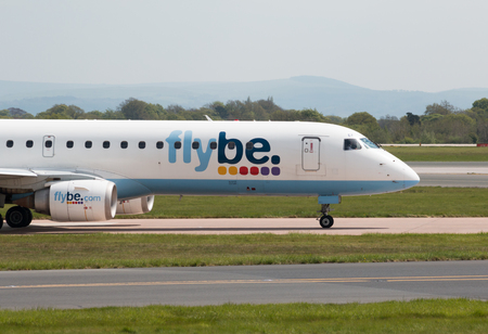 Flybe Embraer ERJ-195LR narrow-body medium-range twin-engine jet airliner (G-FBEF) taxiing on Manchester International Airport tarmac.のeditorial素材