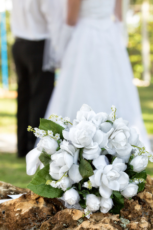 white bouquet on a rock and the couple in the backgroundの写真素材