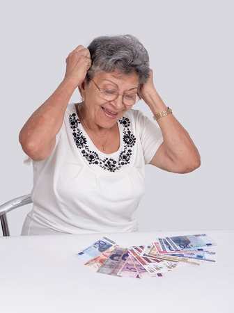 An happy old woman wearing glasses looking moneyの写真素材