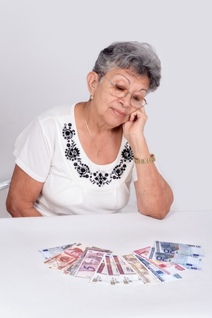 An old woman wearing glasses looking moneyの写真素材