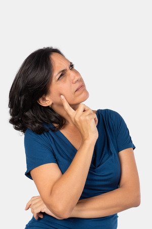 A woman thinking,with one finger touching her face, she is wearing a blue blouseの写真素材