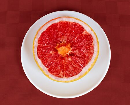 A half of a grapefruit on a white disk and redの写真素材