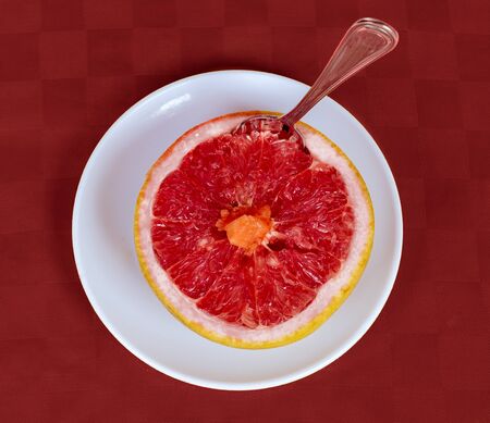 A half of a grapefruit on a white disk and redの写真素材
