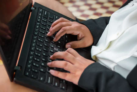 Hands of a Latin woman on the keyboard of a black laptop.の写真素材