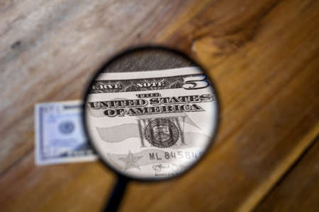 A colorless view through a magnifying glass of the letters, The United States of America, on a one dollar bill. The rest of the images are in color and out of focus.の写真素材