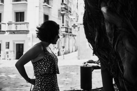 Young girl with short hair looking at an old tree in black and whiteの写真素材