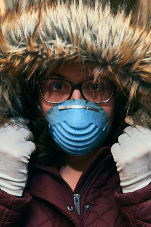 Portrait of a girl wearing a hood, glasses, gloves and a mask for protection against coronavirus