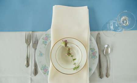 Vintage place setting on a table with silverware and napkin.  Antque fork, knife and spoon included...