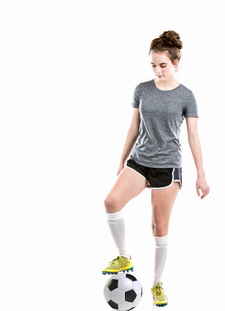 Athletic teen girl playing soccer with ball, shin guards and soccer cleats.