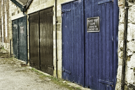 Row of grungy painted garage doors in an urban environmnet with a Please keep clear sign on oneの写真素材