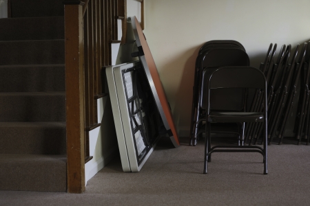 Folding tables and chairs stacked at the bottom of a stairwell in an entertainment venue, meeting hall or schoolの写真素材