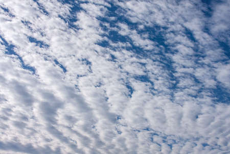 White, puffy clouds against a dark blue skyの写真素材