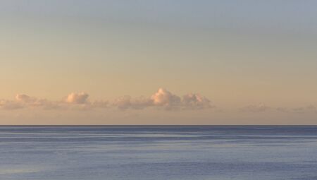 Sunset with a calm sea and small clouds on the horizon lineの写真素材