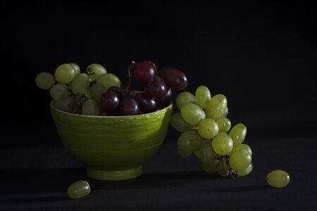 Grapes in a green bamboo bowl on a black backgroundの写真素材