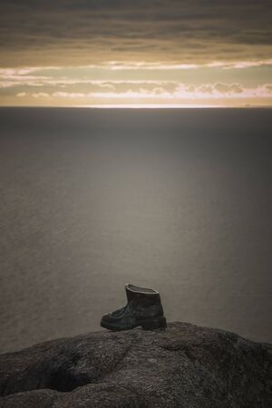 Sculpture of a bronze boot dedicated to the pilgrims of the Way of Saint James in Finisterre, Spain, at sunsetの写真素材