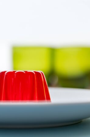 Close-up of a strawberry jelly dessert with a two green glasses in the backgroundの写真素材
