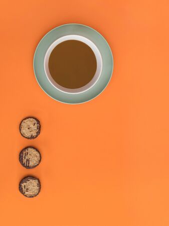 Chocolate bowl on a green light plate and three cookies. Orange background. Copy space.の写真素材
