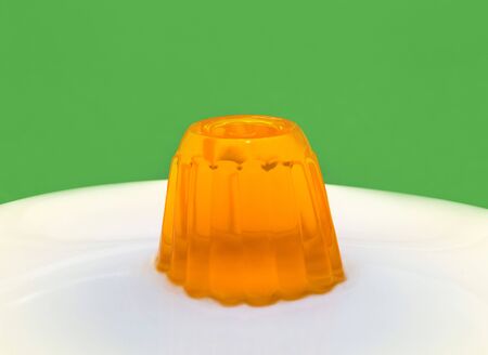 Close up of a orange gelatin on a white plate. Green background.の写真素材