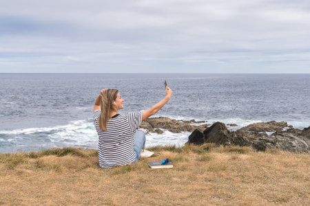 Woman taking a self-portrait with a mobile phone sitting in the park